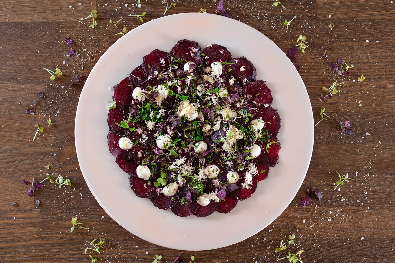 White plate with thinly sliced ​​beetroot topped with horseradish & yogurt