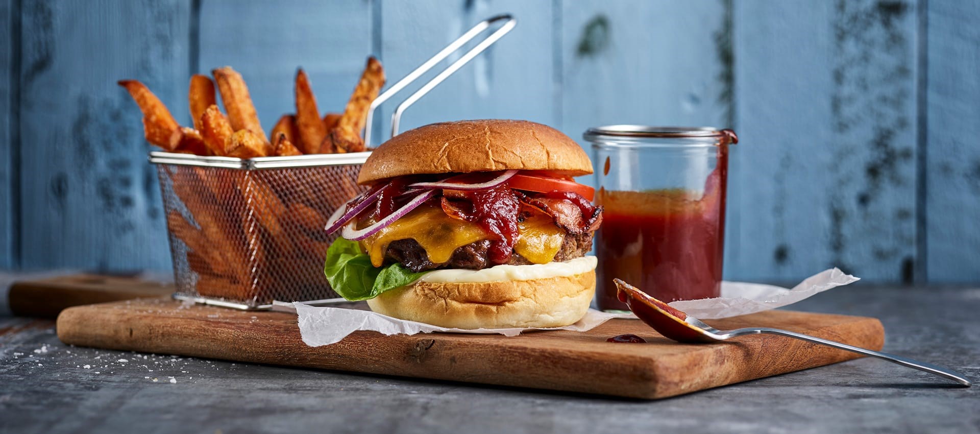 Cheese burger med pommes frites og saus på en på en fjøl